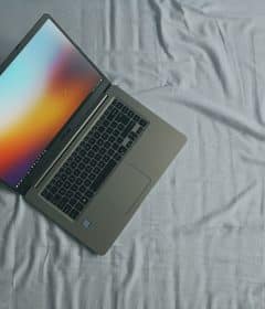 gray Asus laptop on white bed sheet