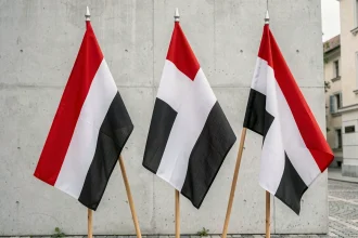 Trois drapeaux aux couleurs rouge blanc noir et noir blanc rouge accrochés côte à côte sur des mâts en bois, illustrant les différences entre ces drapeaux nationaux
