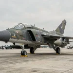 F-4 Phantom II exposé sur un tarmac de musée aéronautique, vue trois-quarts révélant le camouflage militaire usé et les détails de structure