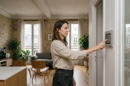 Femme utilisant un panneau domotique mural dans un appartement parisien moderne avec plafonds haussmanniens