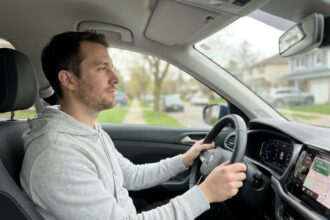 Homme au volant d'une voiture garée, adoptant une attitude calme et réfléchie avant de prendre la route