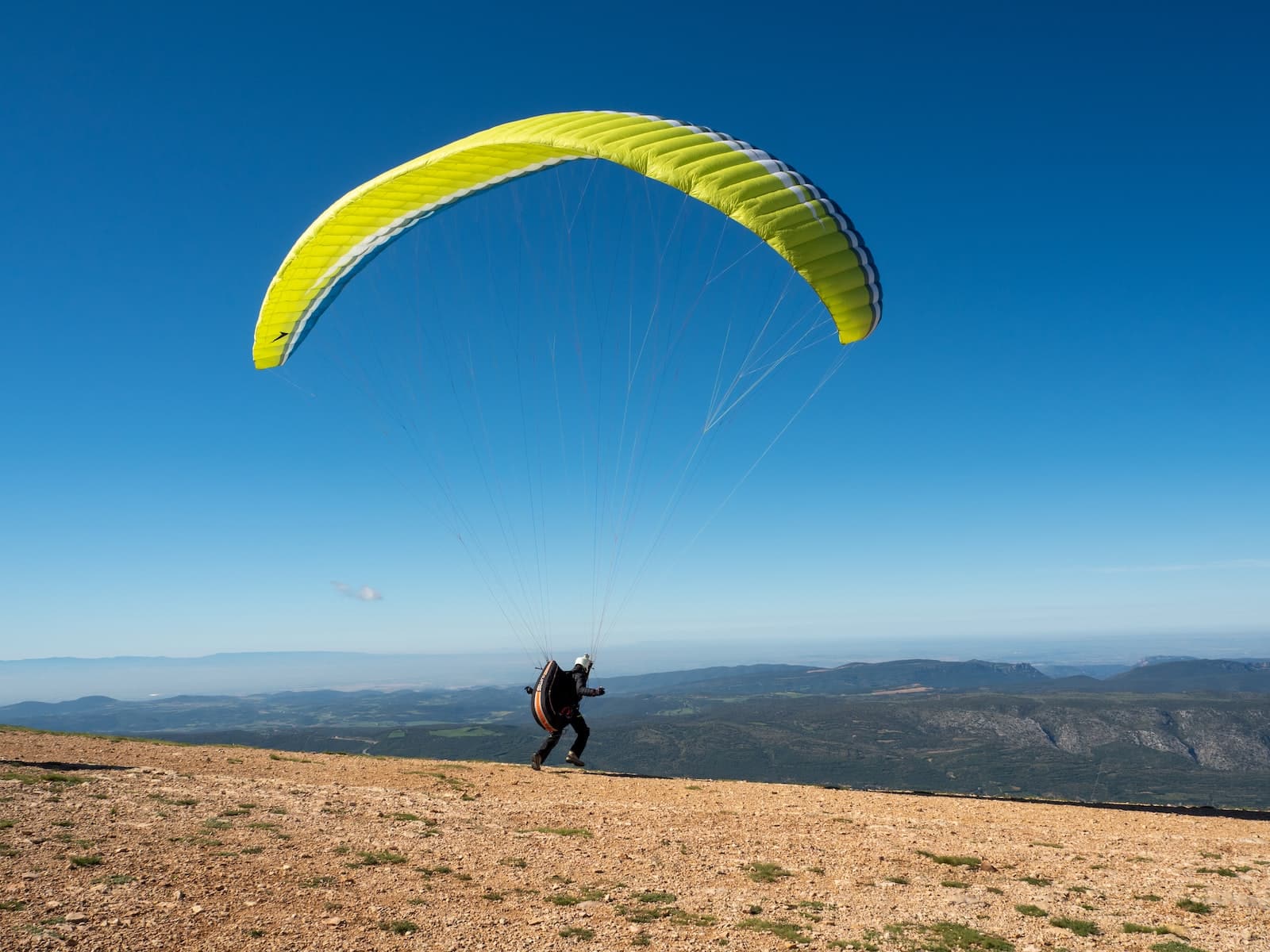 person in black shirt and pants with yellow parachute in the sky
